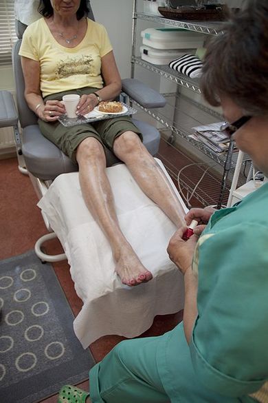 Hoitaja tekee jalkahoitoa asiakkaalle